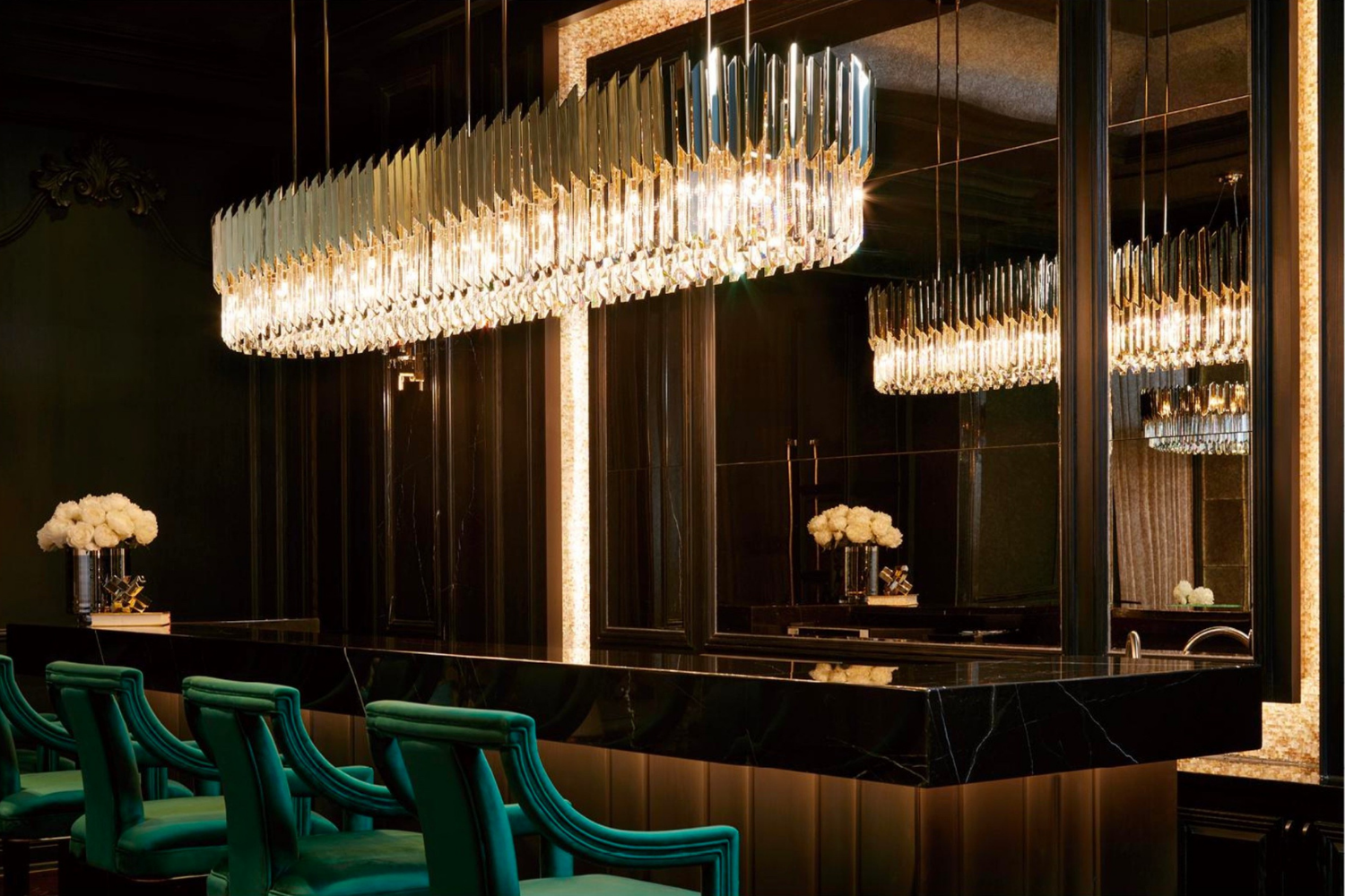 Grand scale linear crystal chandelier illuminating a luxury bar interior, showcasing architectural proportion, precision detailing, and refined materiality.