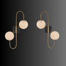 Two alabaster wall lights with curved brass frame and glowing stone spheres