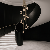Cascading alabaster chandelier illuminating a black curved staircase in luxury home