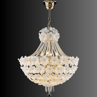 Floral chandelier glowing softly with hand-blown white glass flowers and gold detailing.