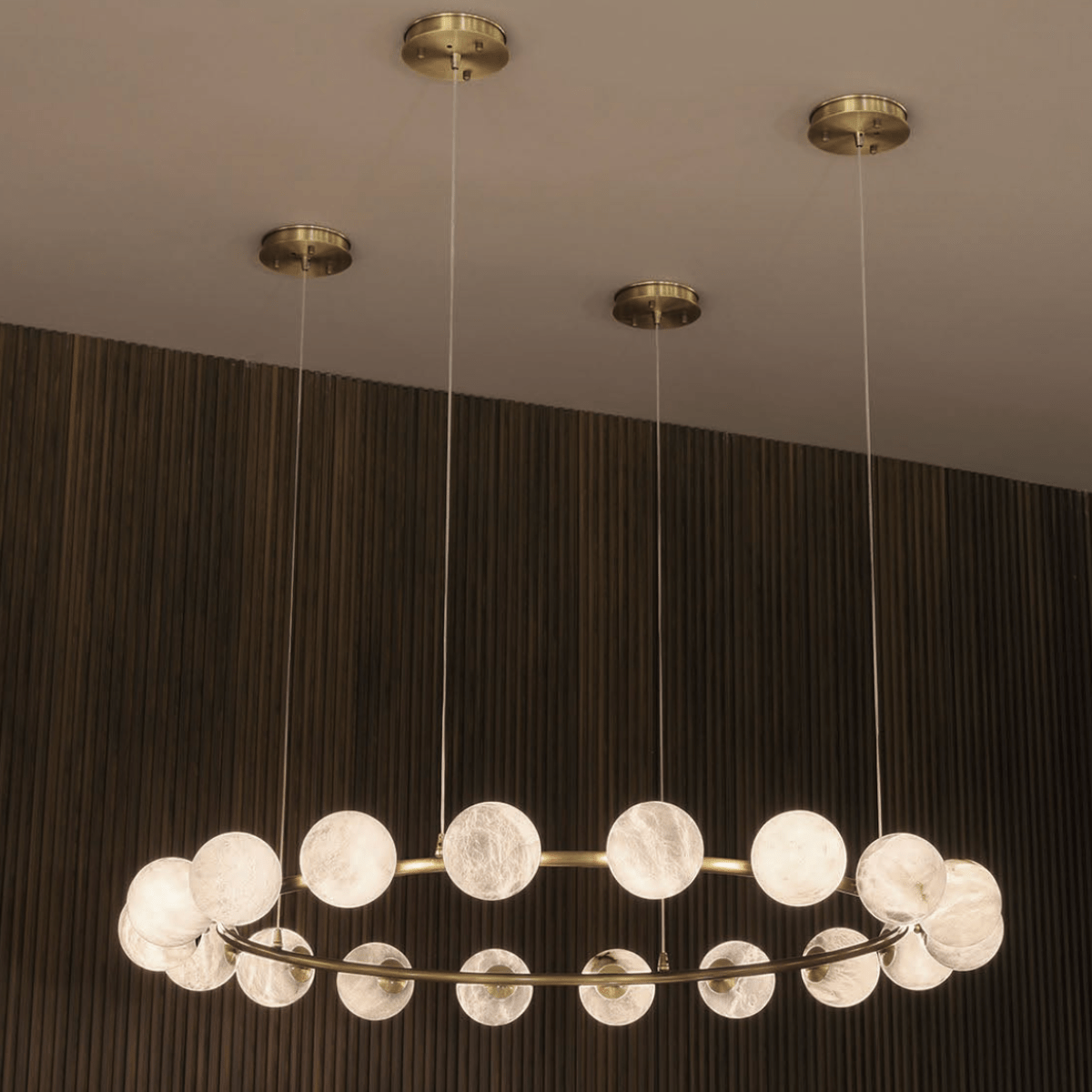 Brass ceiling canopies supporting the suspended Galaxia alabaster ring chandelier.