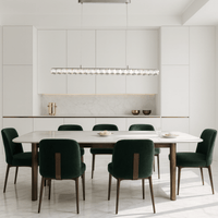 Halo Luxe Elara linear crystal chandelier installed in a modern white dining room with green velvet chairs.