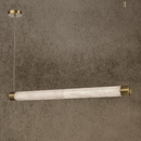 Linear alabaster pendant with brass caps suspended from ceiling, glowing softly in a modern luxury interior.