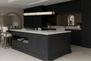 Alabaster Lumen pendant light installed above a black luxury kitchen island with brass accents and stone finishes.