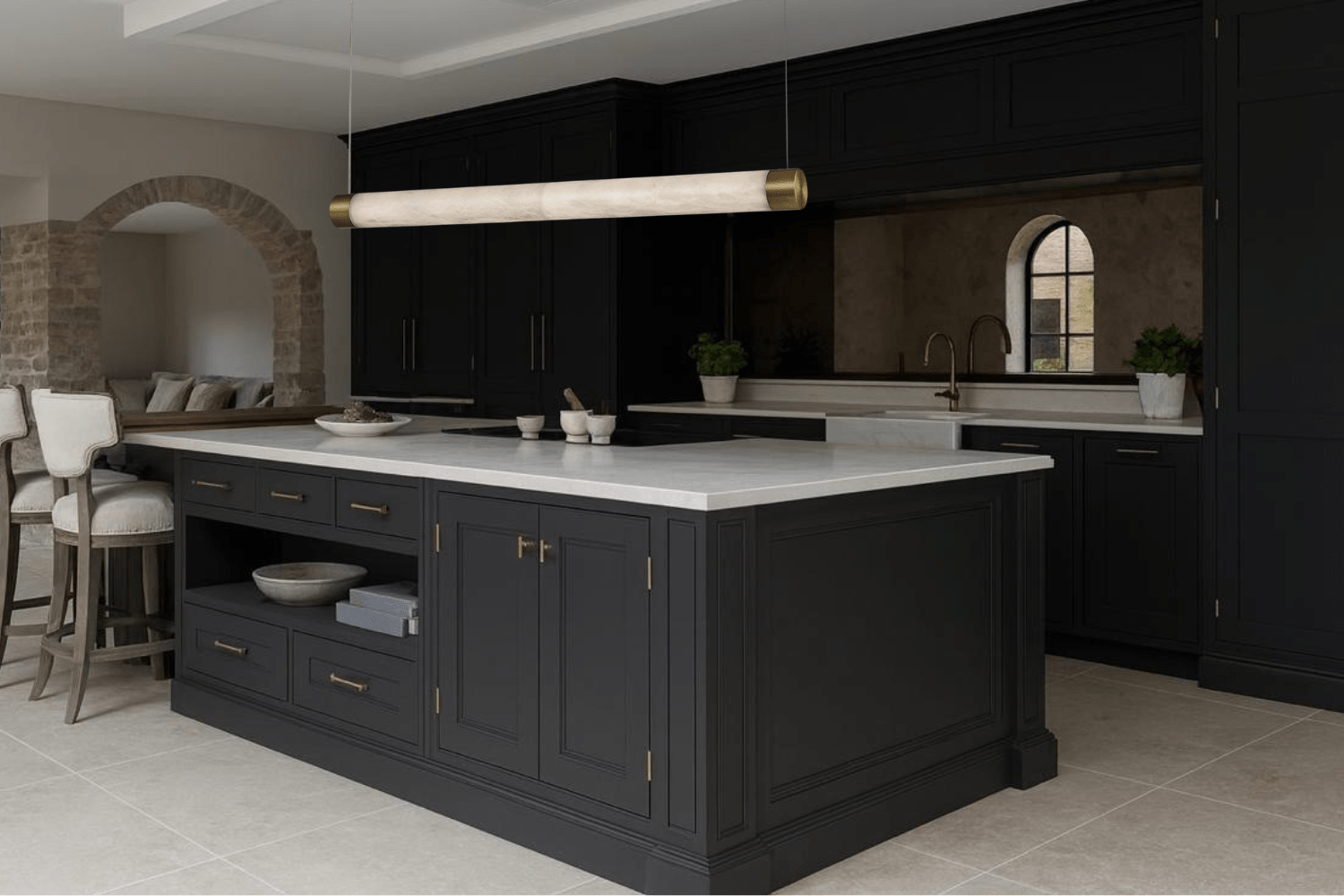 Alabaster Lumen pendant light installed above a black luxury kitchen island with brass accents and stone finishes.