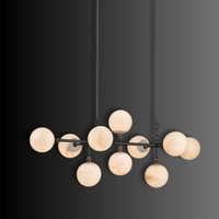 Architectural linear chandelier in Spanish alabaster and copper shown illuminated on dark background.