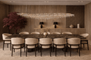 Luxury linear chandelier installed above grand dining table in a refined interior setting