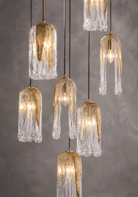 Close-up of Aurora Lava Murano-style hand-blown glass pendants showing golden glow, textured glass detail, and brass fittings