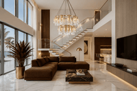 Modern living room with a Aurora Maestra chandelier, brown sectional sofa, and marble coffee table.