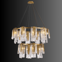 Aurora Maestra chandelier shown on a black background, cascading Murano-style glass and polished brass double-tier design.
