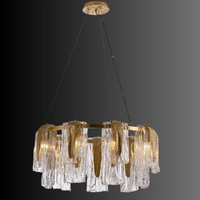 Aurora Sublime chandelier on a dark grey backdrop showing layered glass panels and brass structure for luxury contemporary interiors.