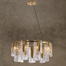 Aurora Sublime chandelier in brass with Murano-style glass panels, showing flowing textures and modern sculptural lighting design.