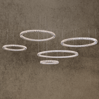 Luxury five-ring crystal chandelier with LED lighting suspended in modern interior, featuring stainless steel and crystals.