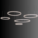 Five radiant crystal rings forming a modern chandelier suspended against a dark background, showcasing LED illumination.