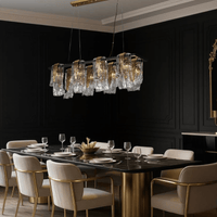 Aurora Magma linear Murano-style glass chandelier illuminating a luxury dining room with brass accents and refined modern décor.