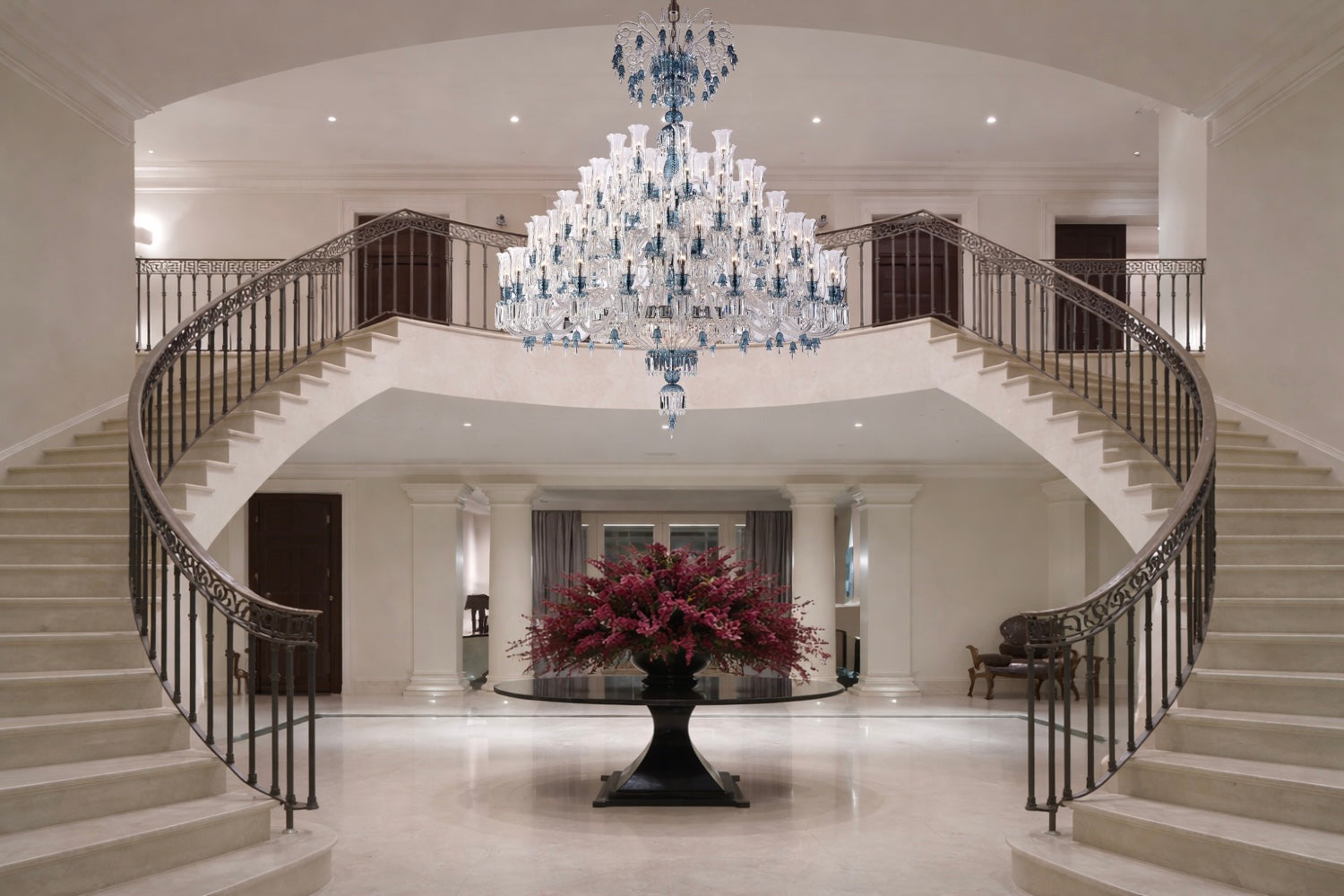 Grand foyer featuring an HDLS crystal chandelier suspended above a double staircase, defining luxury architectural lighting.
