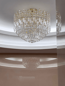 Maurice Doré gold crystal chandelier installed on a modern ceiling, illuminating the space with warm light and layered crystal reflections.