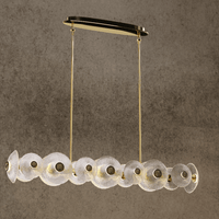 Modernus Linear chandelier with brass-gold frame and Murano-style glass discs displayed against a textured wall.