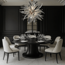 Helios chandelier illuminating a high-end dining room with round black table and modern white chairs.