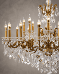 Close-up of Imperial Grace Regina crystal chandelier with bronze-gold arms and illuminated candle bulbs.