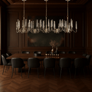 Luce di Roma Vesta chandelier above a luxury dining table, featuring gold frame and champagne crystal spires.