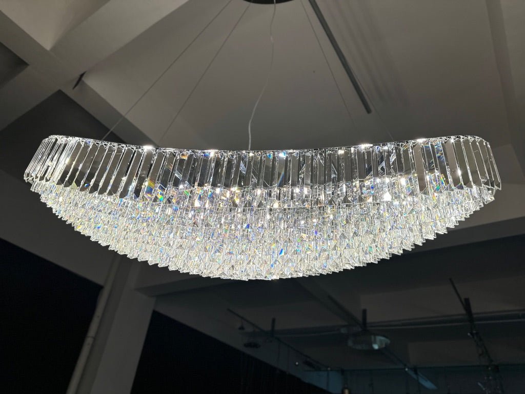 Installed 220 cm Lucerne Arc crystal chandelier illuminated, revealing its sweeping curved profile and layered prisms.