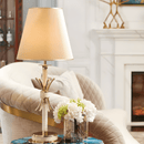 Maria Eleganza gold and Asfour crystal table lamp styled in a luxury interior beside a sofa and decorative florals.