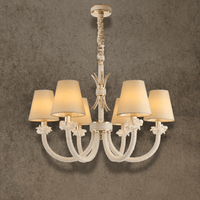 Maria Petite Éclat 6-light gold crystal chandelier with ivory shades and Asfour crystal arms shown a textured grey wall.
