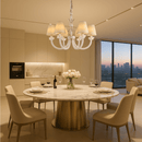 Maria Petite Éclat chandelier illuminating an elegant dining room with a round table and cream chairs.