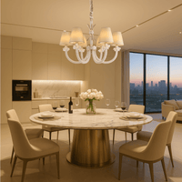 Maria Petite Éclat chandelier illuminating an elegant dining room with a round table and cream chairs.