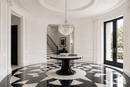 Maurice Argent crystal chandelier above a round table in a luxury black-and-white marble entrance.