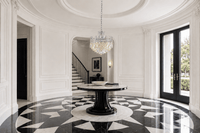 Maurice Argent crystal chandelier above a round table in a luxury black-and-white marble entrance.