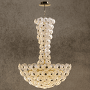 Luxury Modernus Grande chandelier with sculpted Murano-style glass discs and brass-gold frame, on a stone backdrop.