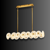 Modernus Linear chandelier by HDLS Lighting on a dark background, showcasing sculpted Murano-style glass discs and brass-gold.