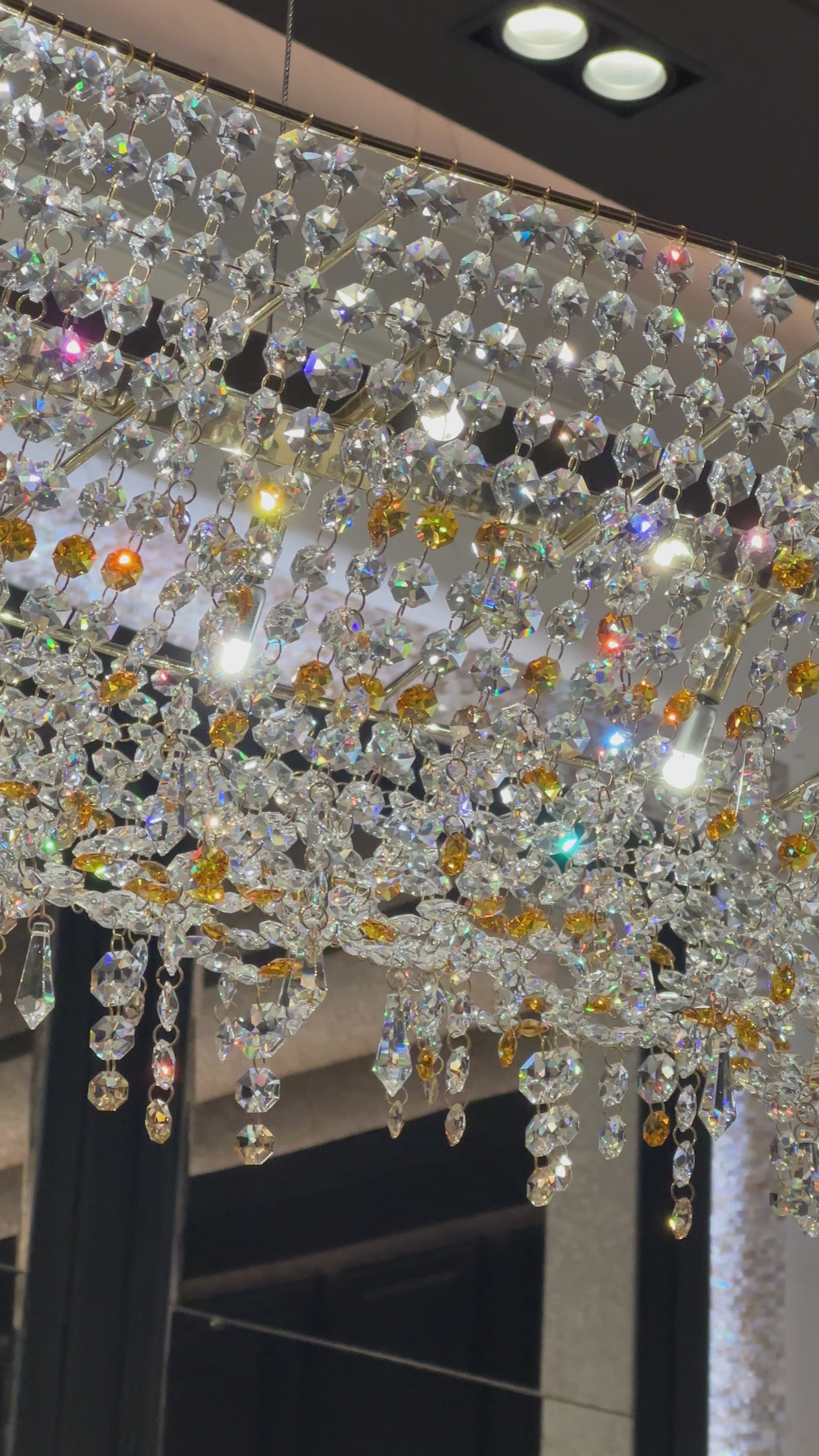 Close-up video of illuminated Asfour crystal and amber accents on the Aurelio Wave Oval chandelier.
