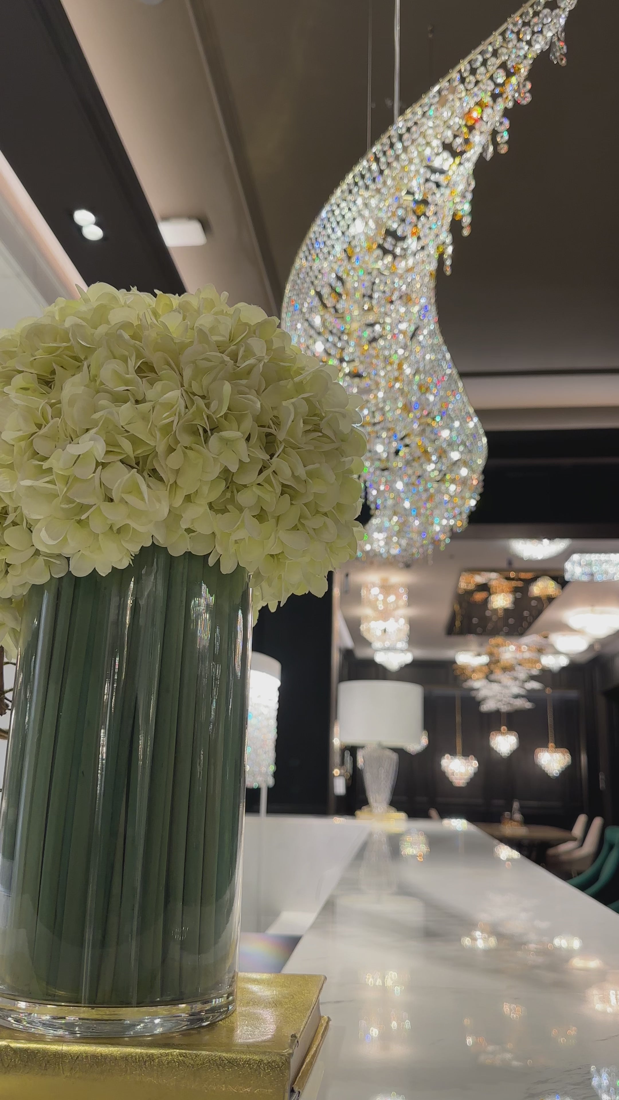 Aurelio Wave chandelier above a luxury bar counter in the HDLS showroom, highlighting sculptural crystal lighting