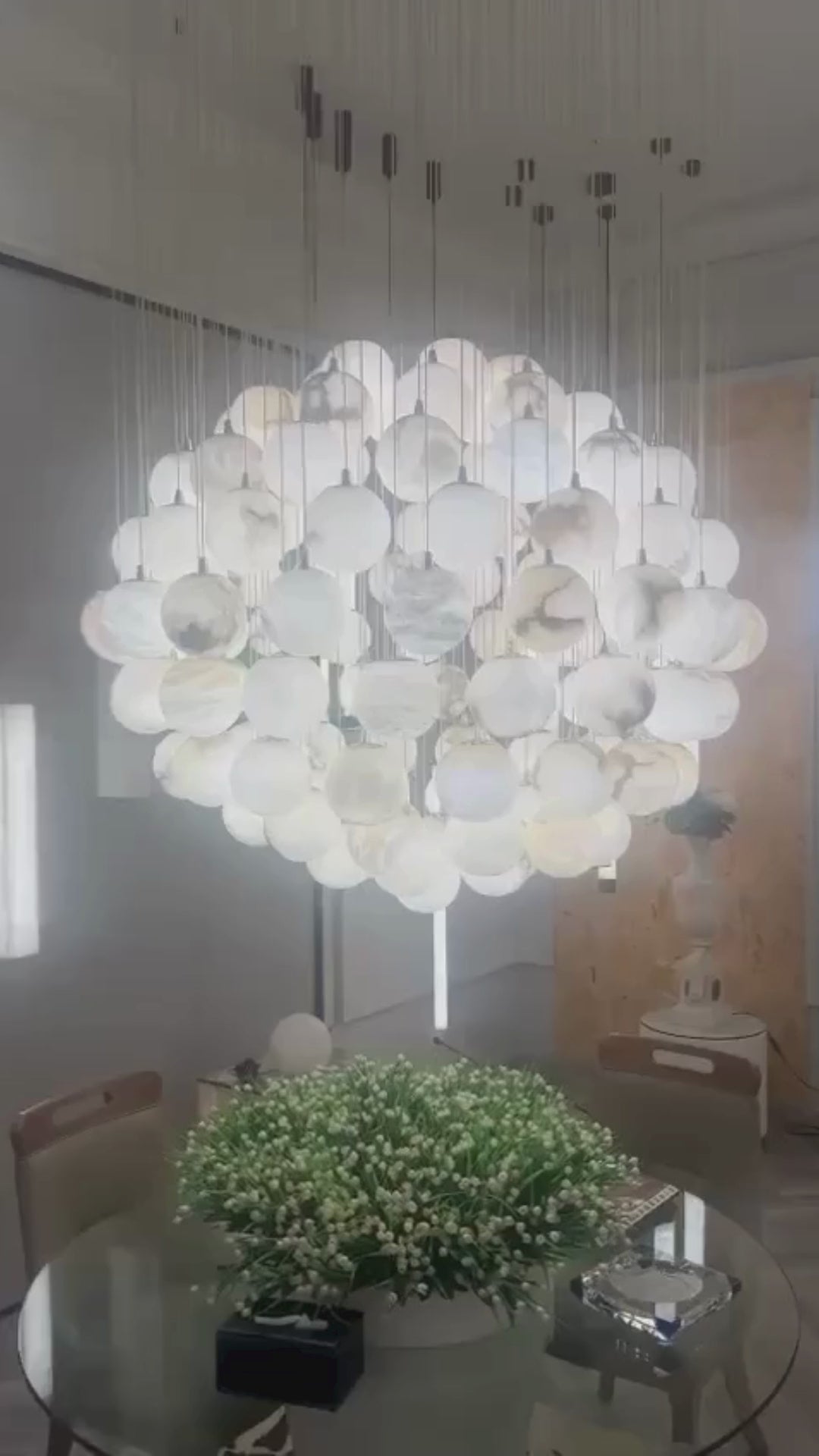 A short video of Alabaster chandelier installed above dining table with suspended sphere composition.
