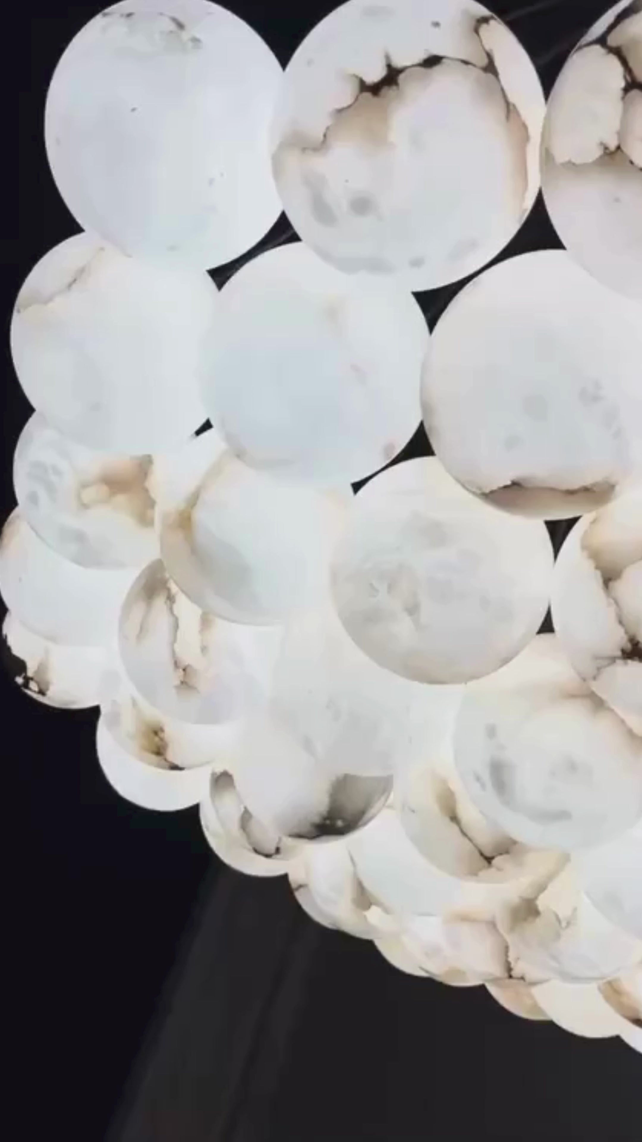 A short video of Alabaster chandelier installed above dining table with suspended sphere composition.