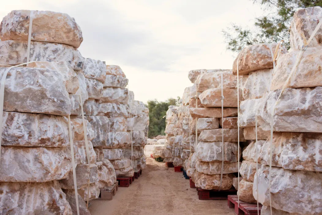 Stacks of raw alabaster stone blocks at a quarry, showcasing the natural texture, veining, and warm tones of genuine alabaster — the foundational material used in HDLS Lighting Ltd’s handcrafted luxury lighting collections.