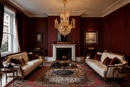 Regency Majestic crystal chandelier in a red-panelled Chelsea living room with classic fireplace and ivory sofas