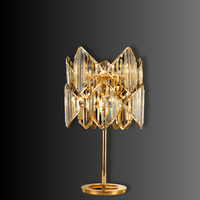 Illuminated Solaris Lyra crystal table lamp showing gold structure and refracted crystal lighting detail.
