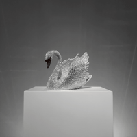 Limited-edition Swarovski crystal swan sculpture VAGHAAR displayed on pedestal with raised wings.