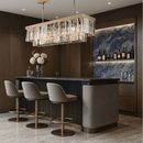Vendôme Prestige 18K gold linear chandelier illuminating a luxury bar island, enhancing stone surfaces and modern interior design details.