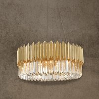 Zarrin Luceris gold crystal chandelier illuminated against textured wall with warm architectural lighting glow.