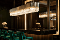 Linear crystal chandelier installed above black marble kitchen island in ultra-luxury interior.