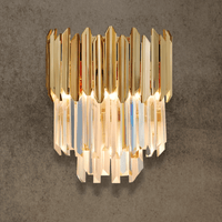 Luxury crystal wall light in 24K gold-plated stainless steel with layered crystal prisms on textured stone wall