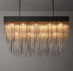 Rainfall Luxe Chandelier in black finish with lights on in front of a grey wall