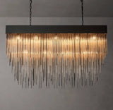 Rainfall Luxe Chandelier in black finish with lights on in front of a grey wall